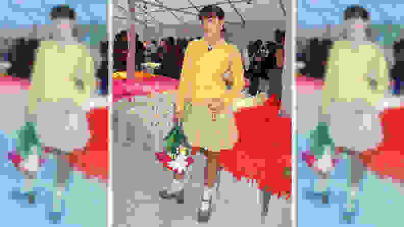 A woman wearing a yellow sweater and a khaki pleated skirt.