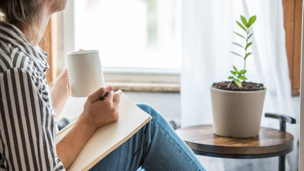 Woman staring at plant with a notebook in her hand