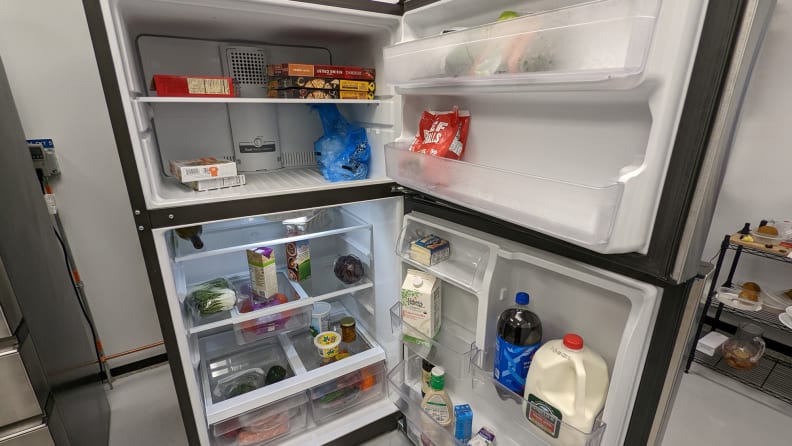 A shot of the interior of both the fridge and freezer compartments. The freezer compartment looks large, and the fridge compartment looks squat underneath it. Both compartments are stocked with food.