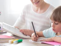Parent and child working together over books at table