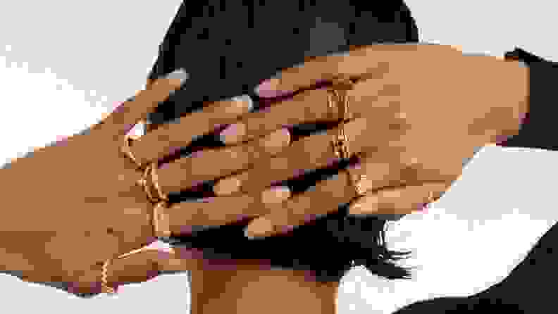 Woman's hands on back of head wearing different gold rings