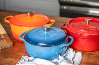 Three colorful Dutch ovens sit on a kitchen counter.