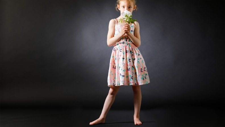 A young girl holding a bouquet of flowers, wearing a pink sundress