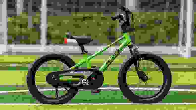 RoyalBaby EZ bike in green sits on a green soccer field in front of a net