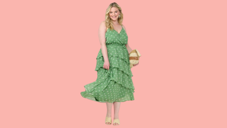 A woman wears a green tiered midi dress with polka dots.