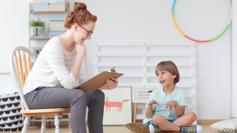 A counselor observes a child patient in a psychotherapy session.