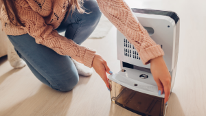 A person removes the water compartment from a dehumidifier