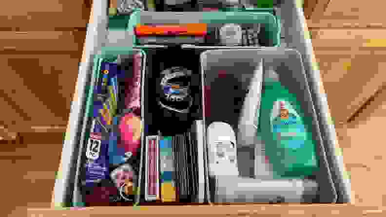 An organized junk drawer pulled open with flashlights, pens, and other small household objects
