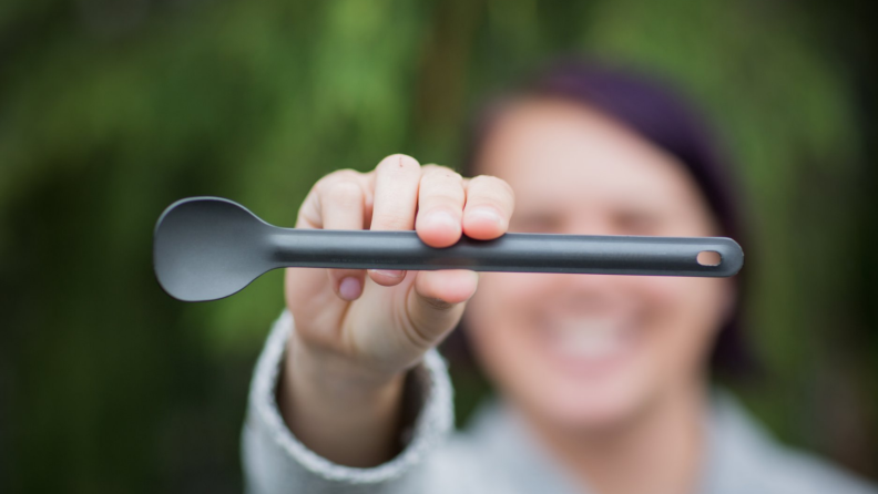 Woman holding a long spoon in front of her face