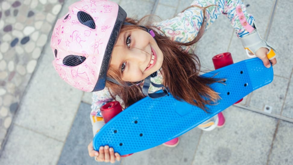 Girl with a skateboard wearing a helmet