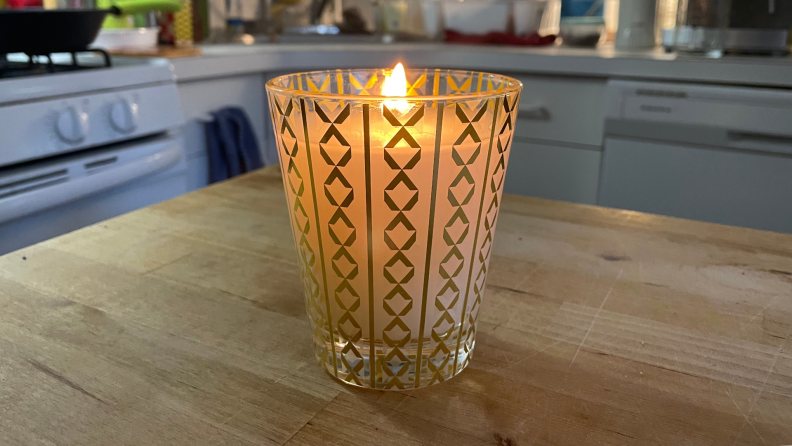 A lit Nest candle sitting on a kitchen counter.