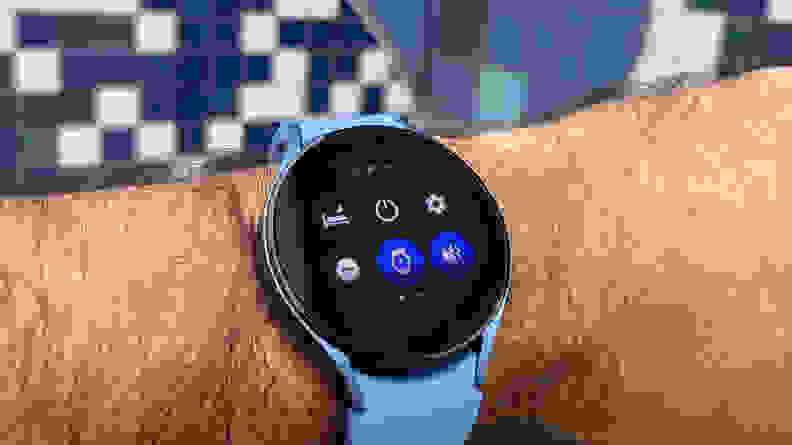A smartwatch with a blue wrist band attached to a perron's wrist