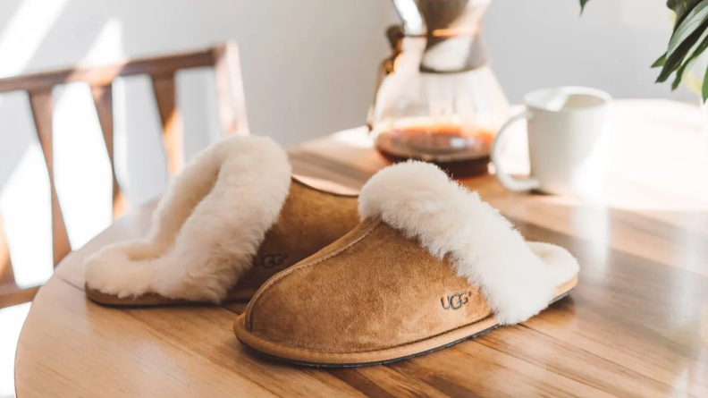 Ugg slippers on a table next to a pot of coffee.