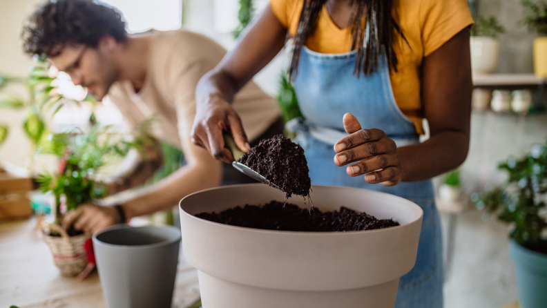 Woman adding soil to a pot for a plant