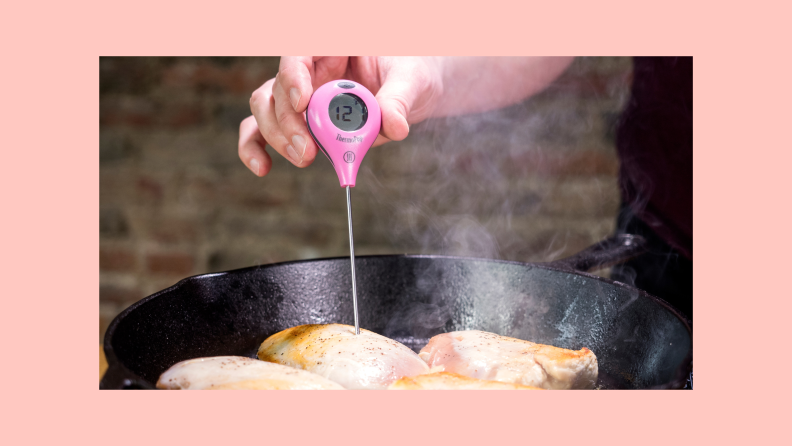 Thermopop digital thermometer taking temp of chicken in skillet with brick wall in background.