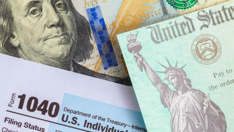 Close-up of a hundred-dollar bill with a 1040 form and an IRS document with the Statue of Liberty.