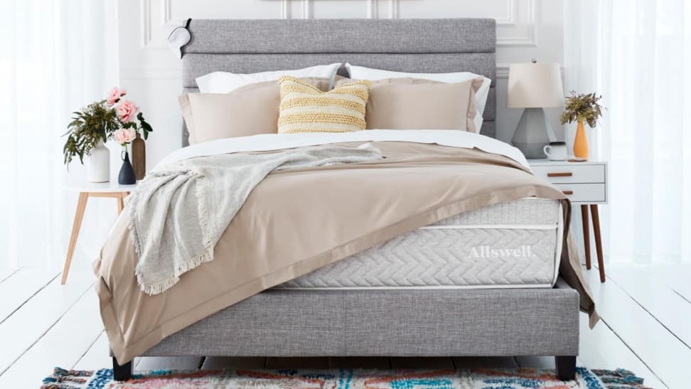 The Allswell supreme mattress with a gray bed frame and tan blankets