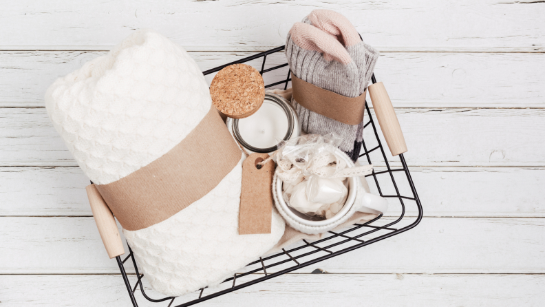 Self-care items with a blanket, socks and cosmetic items inside of wire basket.