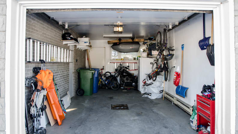 Cluttered suburban garage with small fridge and other assorted items inside.