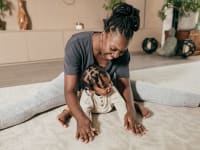 Woman smiling and stretching on floor with baby.