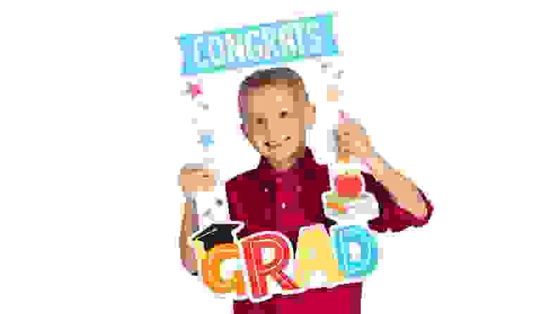 A child smiles from behind a graduation-themed photo frame.