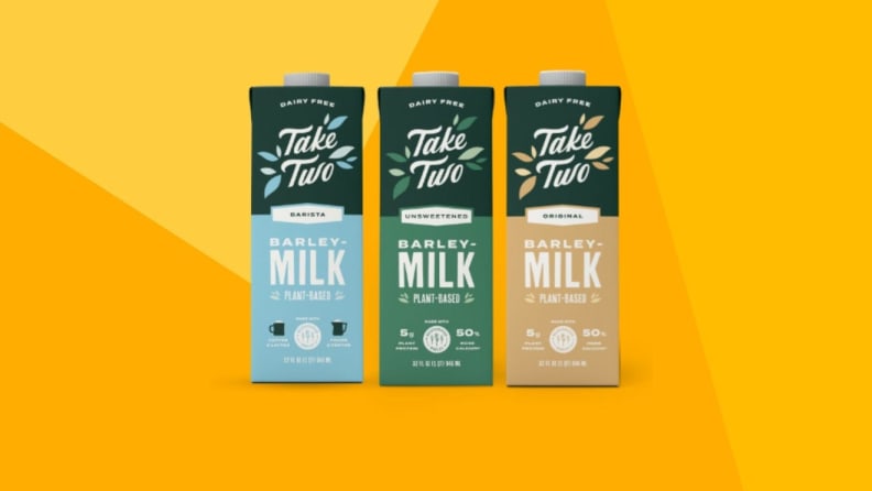 Three cartons of barley milk against a yellow background.