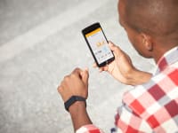 A man wearing the Withings Pulse O2 and looking at the Health Mate app