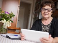 A senior looks at a digital tablet at home.