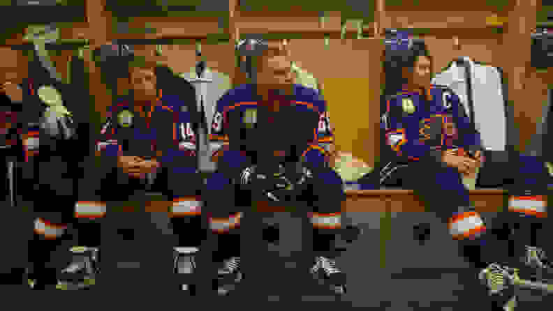 Four hockey players sitting in the changing room
