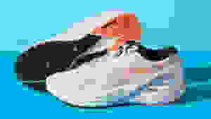 A pair of white and orange running shoes against a blue backdrop.