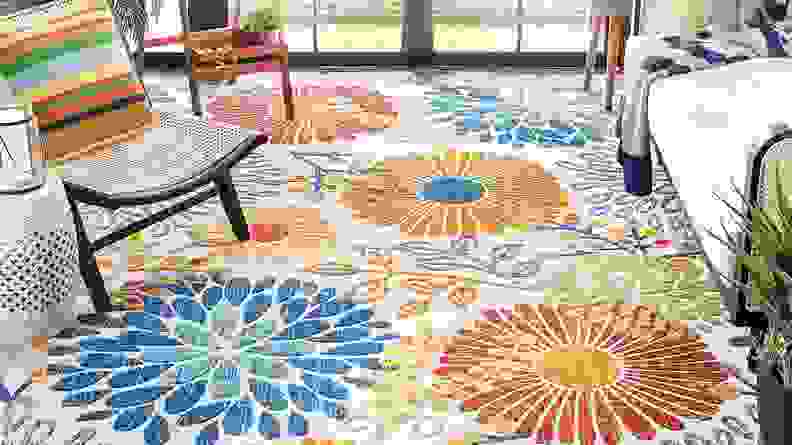 A colorful floral rug on a patio.