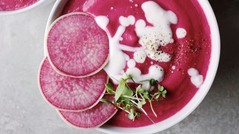 Tazón de sopa de color rosa brillante con rábanos y salsa blanca