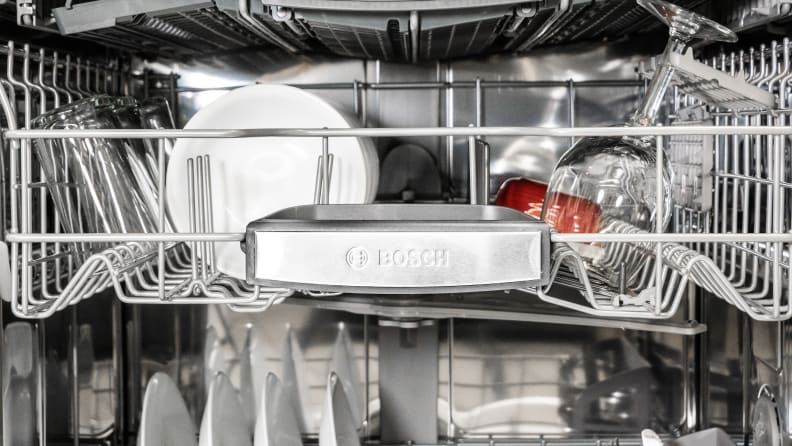 A close-up view of the Bosch logo in silver and a rack inside the dishwasher.
