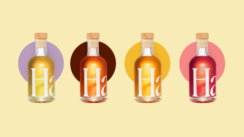 Four colorful mini bottles of assorted aperitifs are arranged in a straight line across a pale yellow background.