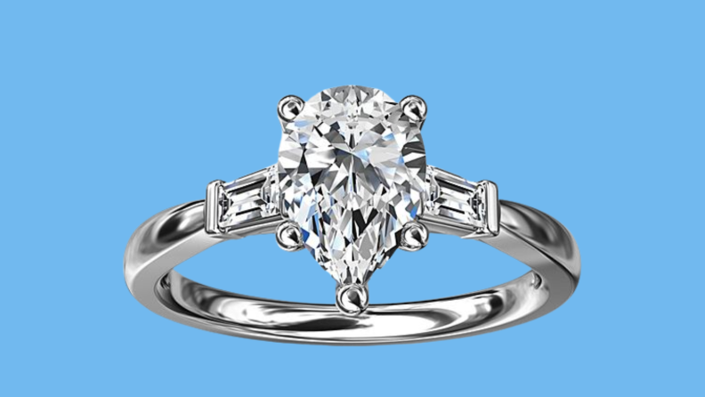 An image of a silver engagement ring with baguette diamonds flanking a larger diamond at the center.
