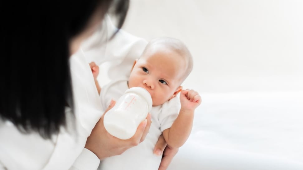 Mother feeding Asian baby with bottle of milk