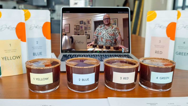 Four samples of coffee in front of a laptop screen showcasing a guided tasting