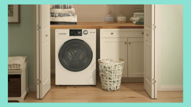 A GE washer-dryer combo is nestled in a small laundry closet with a basket of clothes beside it.