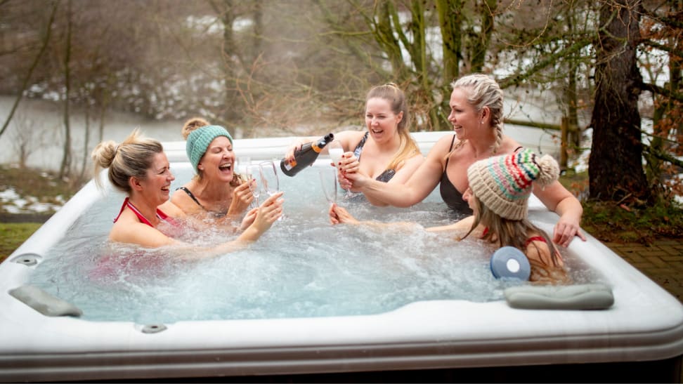 一群朋友坐在热水浴缸里喝香槟。