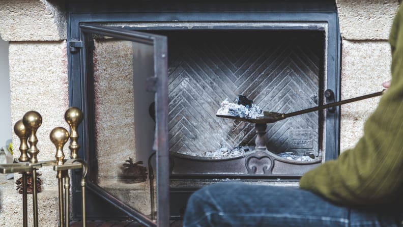 Person scooping hot ashes out of fireplace.