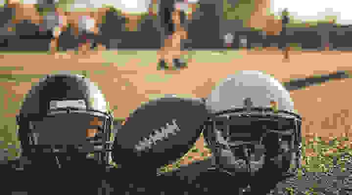 Two helmets and football on field