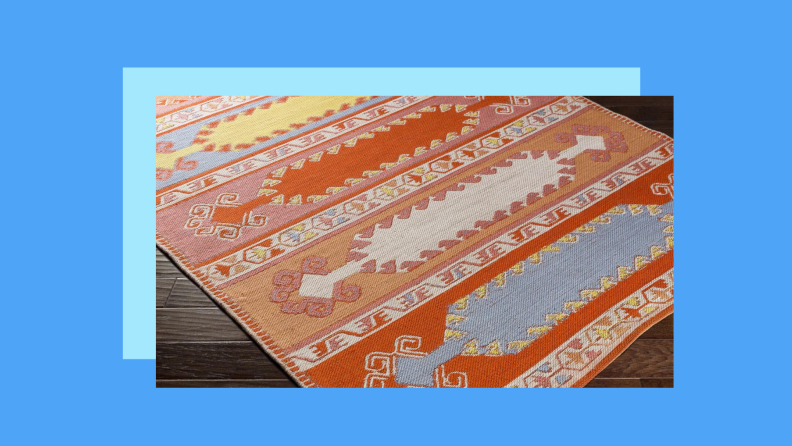 A colorful patterned rug on the floor against a blue background.