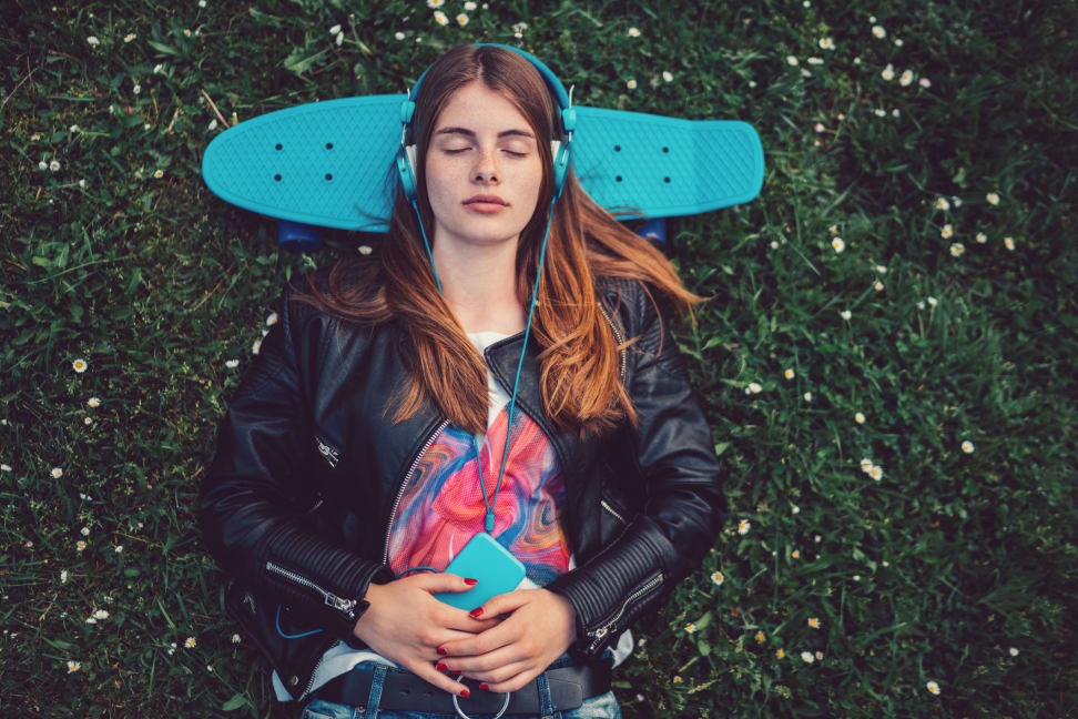 girl listening to music while laying down on her skateboard