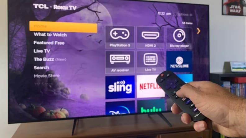 A closeup of the TCL 5-Series feet with a Roku remote sitting on a wooden table.