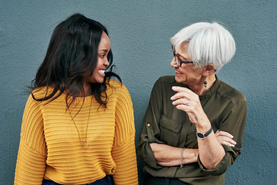 A younger woman and an older woman smiling at each other in conversation