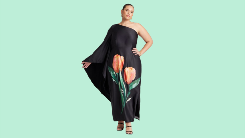 A model wearing a one-shoulder black dress with an oversized tulip print.