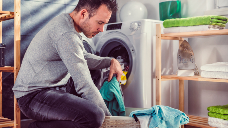 White man squats and sorts laundry