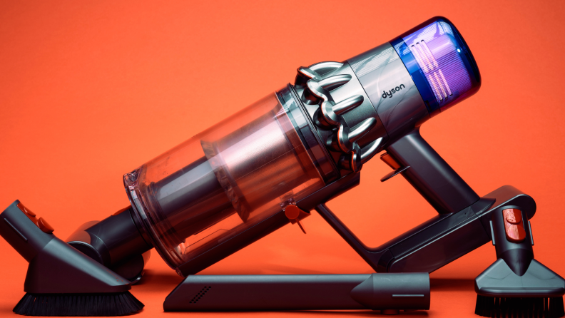 Purple Dyson vacuum with tool add-ons on orange backdrop