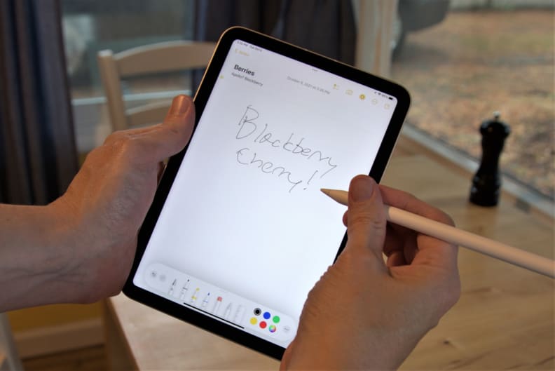 Someone writing on a computer tablet with a stylus.