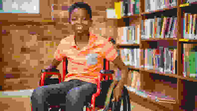 A young boy sitting on a wheelchair with a smile on his face.